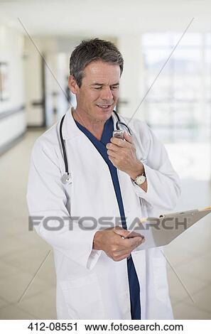 Doctor talking into dictaphone View Large Photo Image Stock Image - Doctor talking into dictaphone. Fotosearch