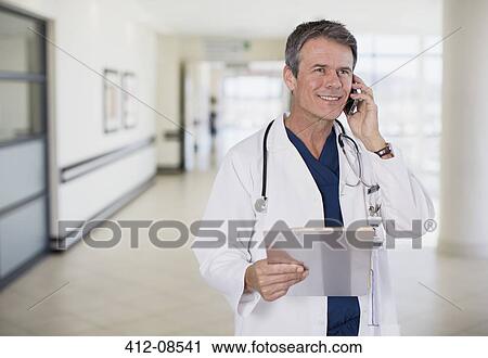 Doctor talking on cell phone in hospital corridor View Large Photo Image Stock Image - Doctor talking on cell phone in hospital corridor. Fotosearch
