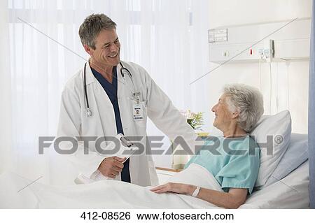 Doctor talking to elderly patient in hospital View Large Photo Image Stock Photograph - Doctor talking to elderly patient in hospital. Fotosearch