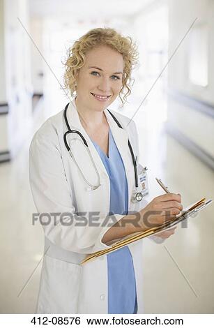 Doctor writing on clipboard in hospital corridor View Large Photo Image Stock Photograph - Doctor writing on clipboard in hospital corridor. Fotosearch