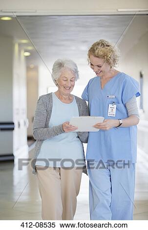 Nurse and aging patient reading chart in hospital corridor View Large Photo Image Stock Photography - Nurse and aging patient reading chart in hospital corridor. Fotosearch