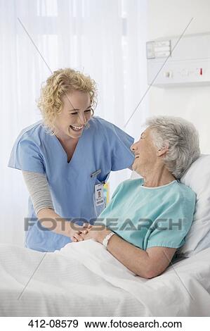 Stock Photo - Nurse and senior patient talking in hospital room. Fotosearch