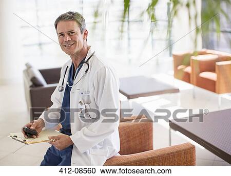 Stock Image - Portrait of smiling doctor in hospital lobby. Fotosearch