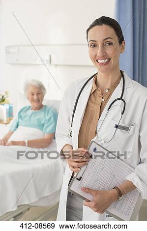 Portrait of smiling doctor with senior patient in background View Large Photo Image Stock Photo - Portrait of smiling doctor with senior patient in background. Fotosearch