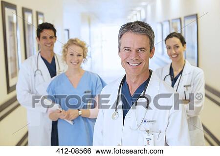 Portrait of smiling doctors and nurse in hospital corridor View Large Photo Image Stock Photograph - Portrait of smiling doctors and nurse in hospital corridor. Fotosearch