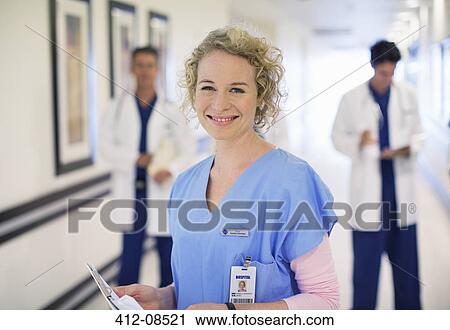 Stock Image - Portrait of smiling nurse in hospital corridor. Fotosearch