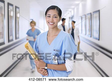 Stock Image - Portrait of smiling nurse in hospital corridor. Fotosearch