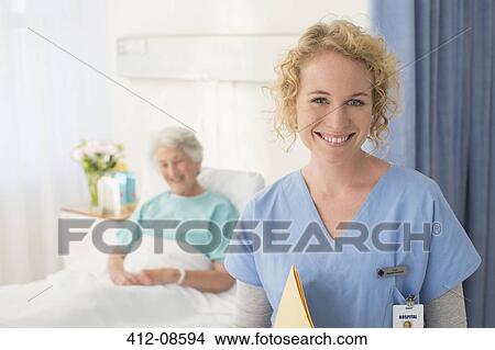 Portrait of smiling nurse with senior patient in background View Large Photo Image Picture - Portrait of smiling nurse with senior patient in background. Fotosearch