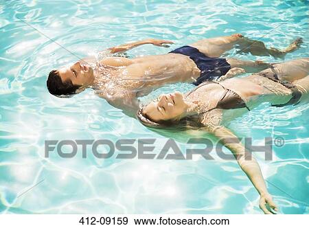 Couple floating in swimming pool View Large Photo Image Stock Photo - Couple floating in swimming pool. Fotosearch