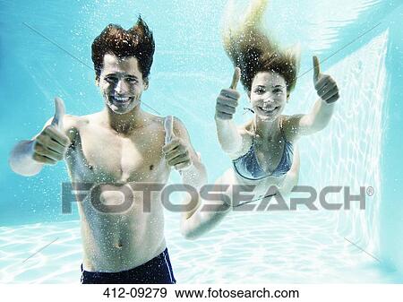 Couple giving thumbs up underwater in swimming pool View Large Photo Image Stock Photo - Couple giving thumbs up underwater in swimming pool. Fotosearch