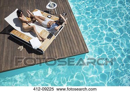 Couple laying on lounge chair at poolside View Large Photo Image Stock Photography - Couple laying on lounge chair at poolside. Fotosearch