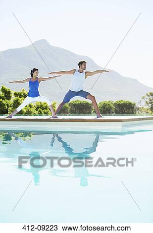 Couple practicing yoga at poolside View Large Photo Image Stock Image - Couple practicing yoga at poolside. Fotosearch