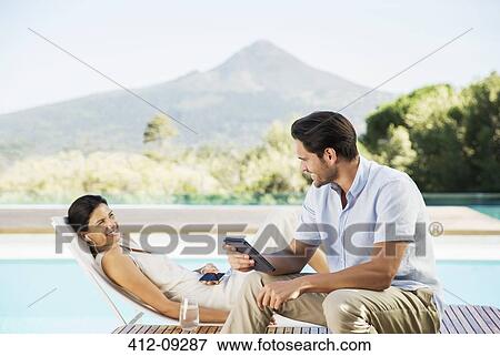Stock Photo - Couple relaxing poolside. Fotosearch