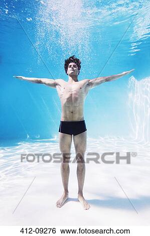 Man standing underwater in swimming pool with arms outstretched View Large Photo Image Stock Photograph - Man standing underwater in swimming pool with arms outstretched. Fotosearch