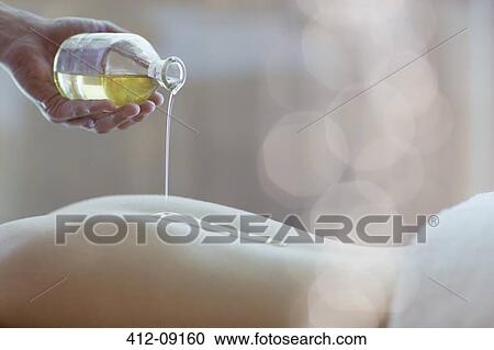 Masseuse pouring oil on woman's back View Large Photo Image Stock Image - Masseuse pouring oil on woman's back. Fotosearch
