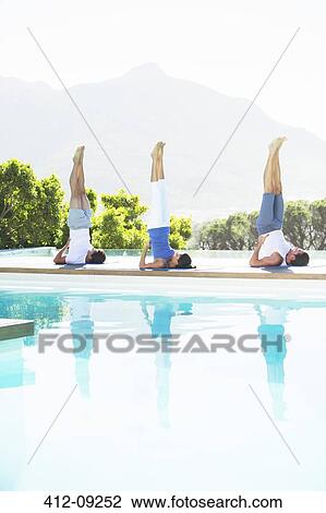 Men and woman practicing yoga poolside View Large Photo Image Stock Image - Men and woman practicing yoga poolside. Fotosearch