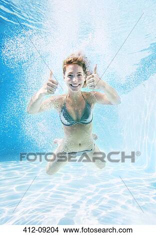 Woman giving thumbs up underwater in swimming pool View Large Photo Image Picture - Woman giving thumbs up underwater in swimming pool. Fotosearch