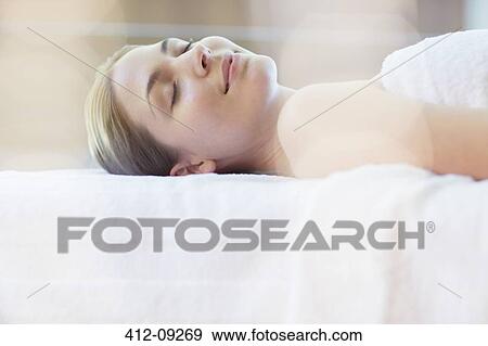 Woman laying on massage table in spa View Large Photo Image Stock Photo - Woman laying on massage table in spa. Fotosearch