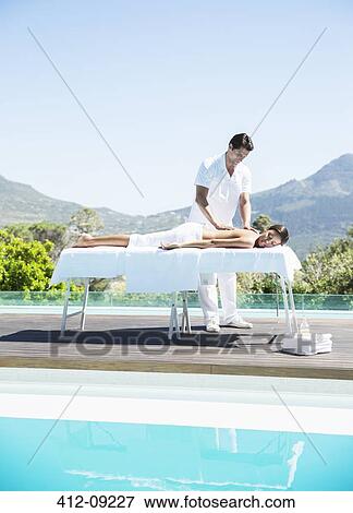 Stock Photo - Woman receiving massage at poolside. Fotosearch