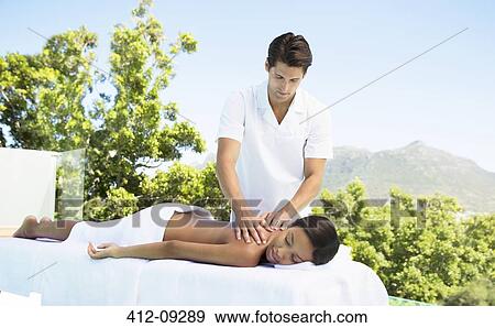Stock Photo - Woman receiving massage on patio at spa. Fotosearch