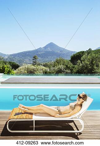 Woman relaxing on lounge chair at poolside View Large Photo Image Stock Image - Woman relaxing on lounge chair at poolside. Fotosearch