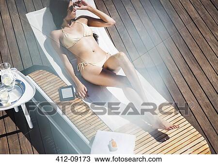 Woman relaxing on lounge chair View Large Photo Image Stock Image - Woman relaxing on lounge chair. Fotosearch
