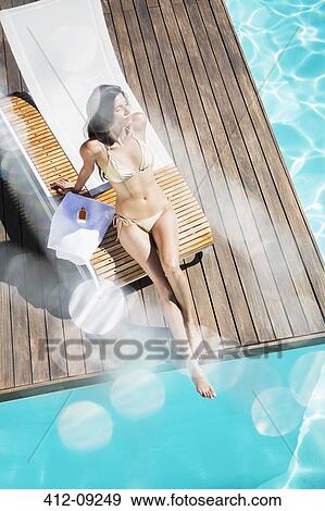 Woman relaxing poolside View Large Photo Image Stock Photo - Woman relaxing poolside. Fotosearch