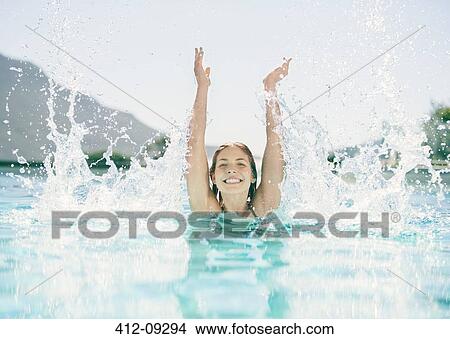 Picture - Woman splashing in swimming pool. Fotosearch