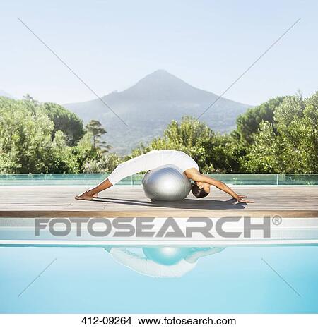 Woman stretching over fitness ball at poolside View Large Photo Image Picture - Woman stretching over fitness ball at poolside. Fotosearch