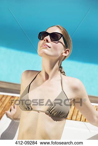 Woman sunbathing at poolside View Large Photo Image Picture - Woman sunbathing at poolside. Fotosearch