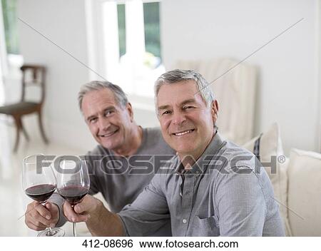 Stock Photograph - Portrait of senior men toasting wine glasses. Fotosearch