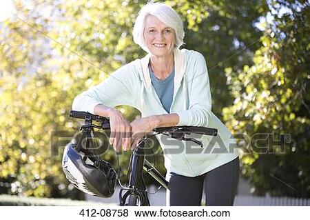 Stock Photo - Portrait of senior woman leaning on bicycle. Fotosearch