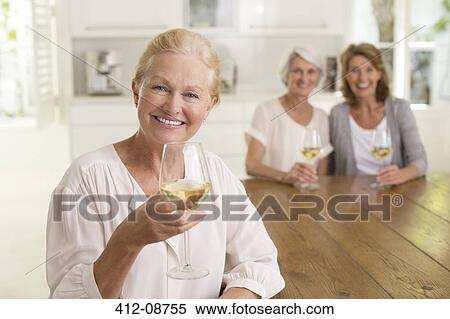 Stock Photography - Portrait of smiling senior women drinking white wine. Fotosearch