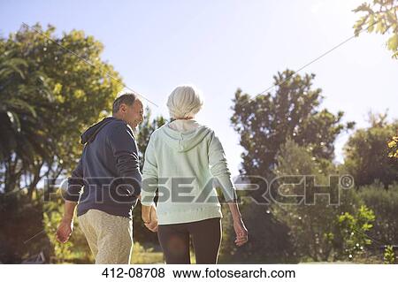 Senior couple holding hands and walking in park View Large Photo Image Stock Photo - Senior couple holding hands and walking in park. Fotosearch