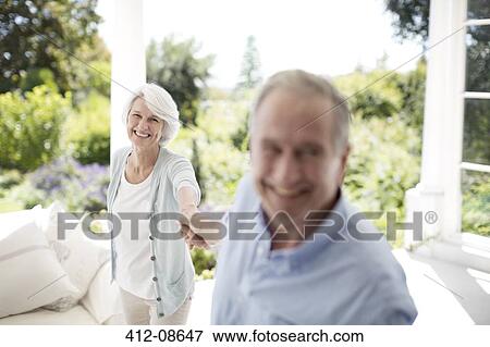 Stock Photo - Senior couple holding hands on patio. Fotosearch