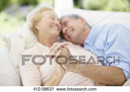 Senior couple holding hands on sofa View Large Photo Image Stock Photo - Senior couple holding hands on sofa. Fotosearch