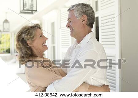 Stock Image - Senior couple hugging on patio. Fotosearch