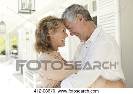 Stock Image - Senior couple hugging on patio. Fotosearch