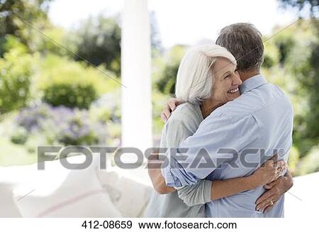 Stock Photo - Senior couple hugging on patio. Fotosearch