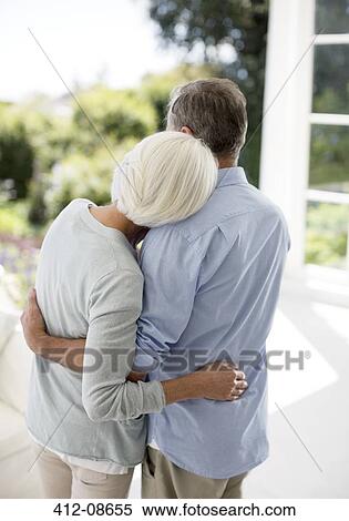 Stock Photography - Senior couple hugging on patio. Fotosearch