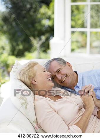 Senior couple laying on patio sofa and holding hands View Large Photo Image Stock Image - Senior couple laying on patio sofa and holding hands. Fotosearch