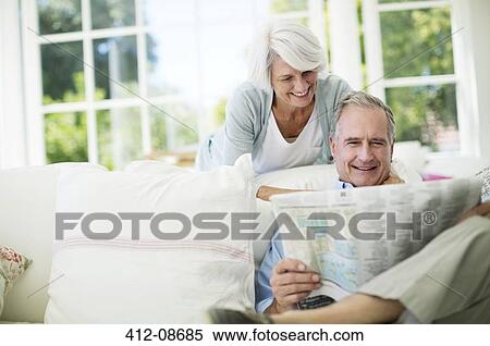 Senior couple reading newspaper on sofa View Large Photo Image Stock Photography - Senior couple reading newspaper on sofa. Fotosearch