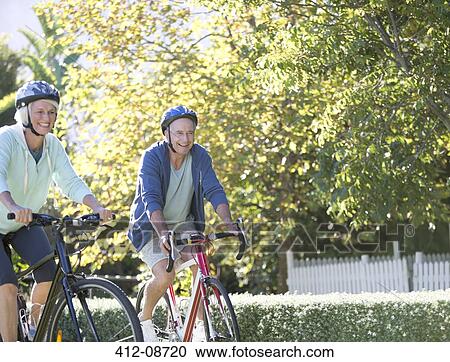 Senior couple riding bicycles in park View Large Photo Image Stock Image - Senior couple riding bicycles in park. Fotosearch