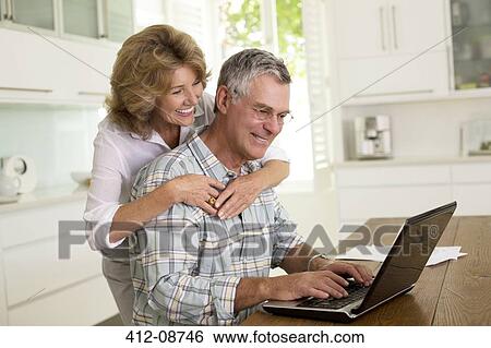 Senior couple using laptop in kitchen View Large Photo Image Stock Photograph - Senior couple using laptop in kitchen. Fotosearch