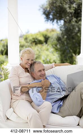 Senior couple using laptop on patio sofa View Large Photo Image Stock Image - Senior couple using laptop on patio sofa. Fotosearch
