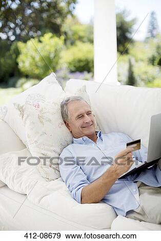 Senior man shopping online on patio sofa View Large Photo Image Stock Photo - Senior man shopping online on patio sofa. Fotosearch
