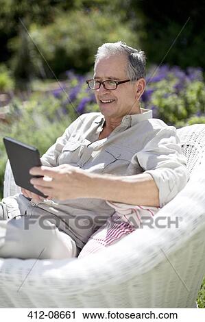 Senior man using digital tablet in armchair View Large Photo Image Stock Image - Senior man using digital tablet in armchair. Fotosearch