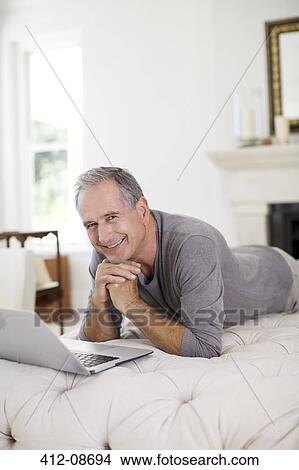 Senior man using laptop in livingroom View Large Photo Image Picture - Senior man using laptop in livingroom. Fotosearch
