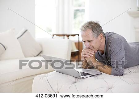 Senior man using laptop in livingroom View Large Photo Image Stock Image - Senior man using laptop in livingroom. Fotosearch