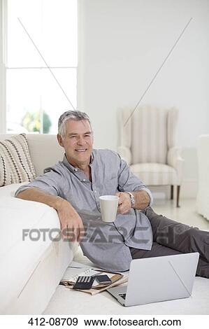 Senior man using laptop on living room floor View Large Photo Image Stock Photo - Senior man using laptop on living room floor. Fotosearch